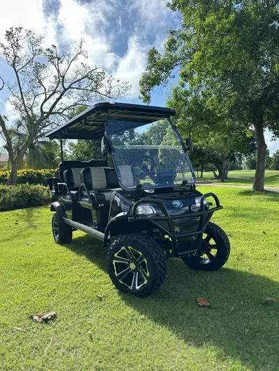 Forester 6 Plus Black en un campo de golf rodeado de árboles, un carrito espacioso y elegante para un recorrido cómodo.