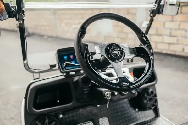 Close-up of the steering wheel and panel of the Carrier 8 Plus white golf cart, featuring advanced controls and a user-friendly interface.