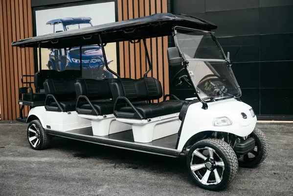 Carrier 8 Plus blanco estacionado frente a una pared gris, un modelo de carritos de golf eléctricos con gran capacidad y diseño moderno