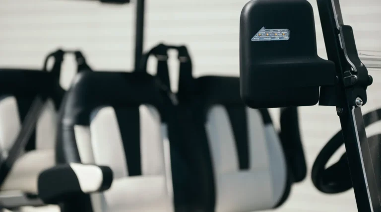 Close-up of golf carts with padded seats and rearview mirror, designed for comfort and safety.